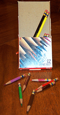 [open pencil box with short pencils in front of it]